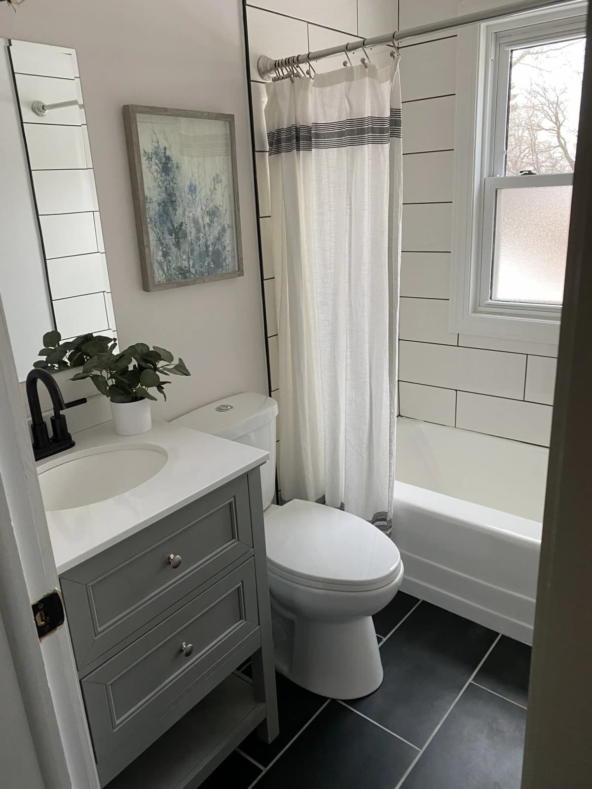 Small bathroom with a gray vanity and white tile tub surround in East Bethel, MN